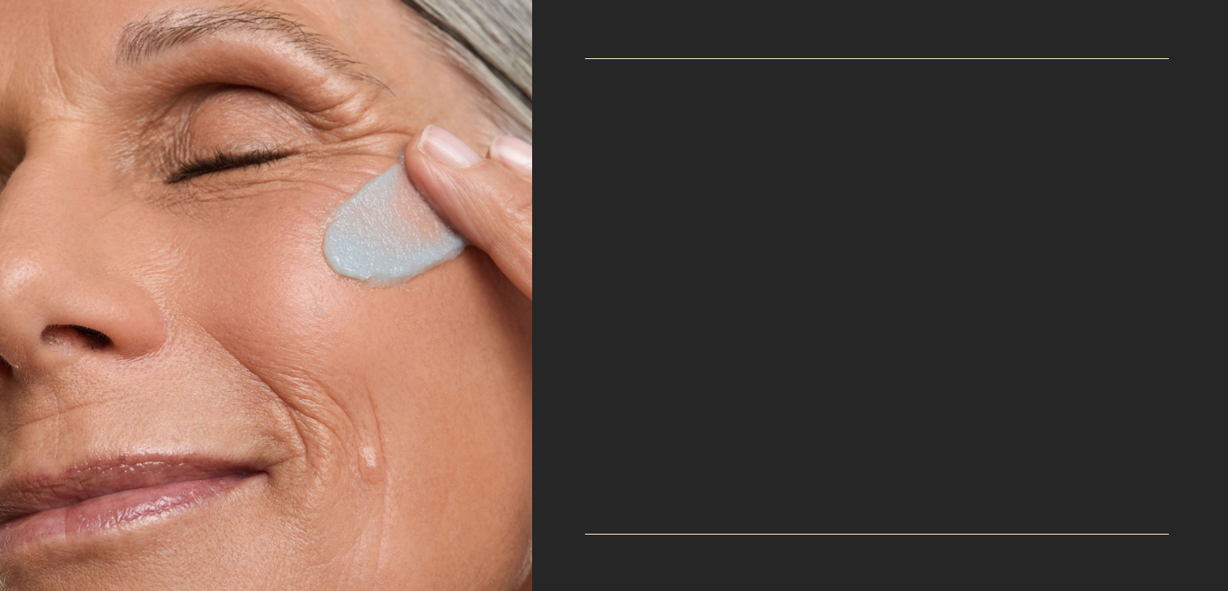 Woman applying eye cream to her face with a black background