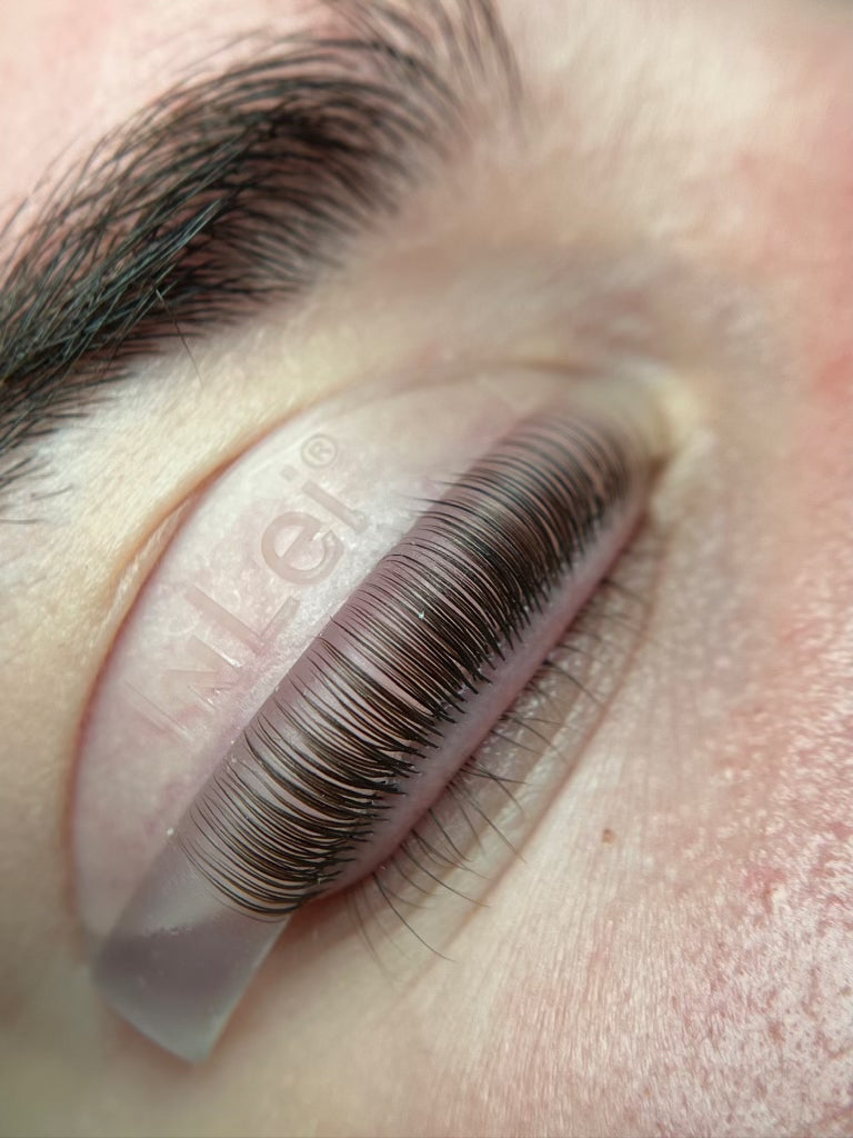 False eyelashes applied to a person's eye with a clear adhesive strip.
