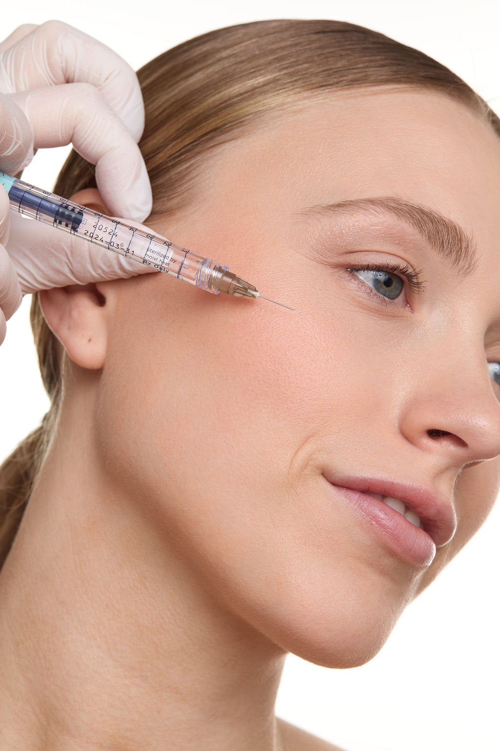Woman receiving facial injection with a syringe on a white background