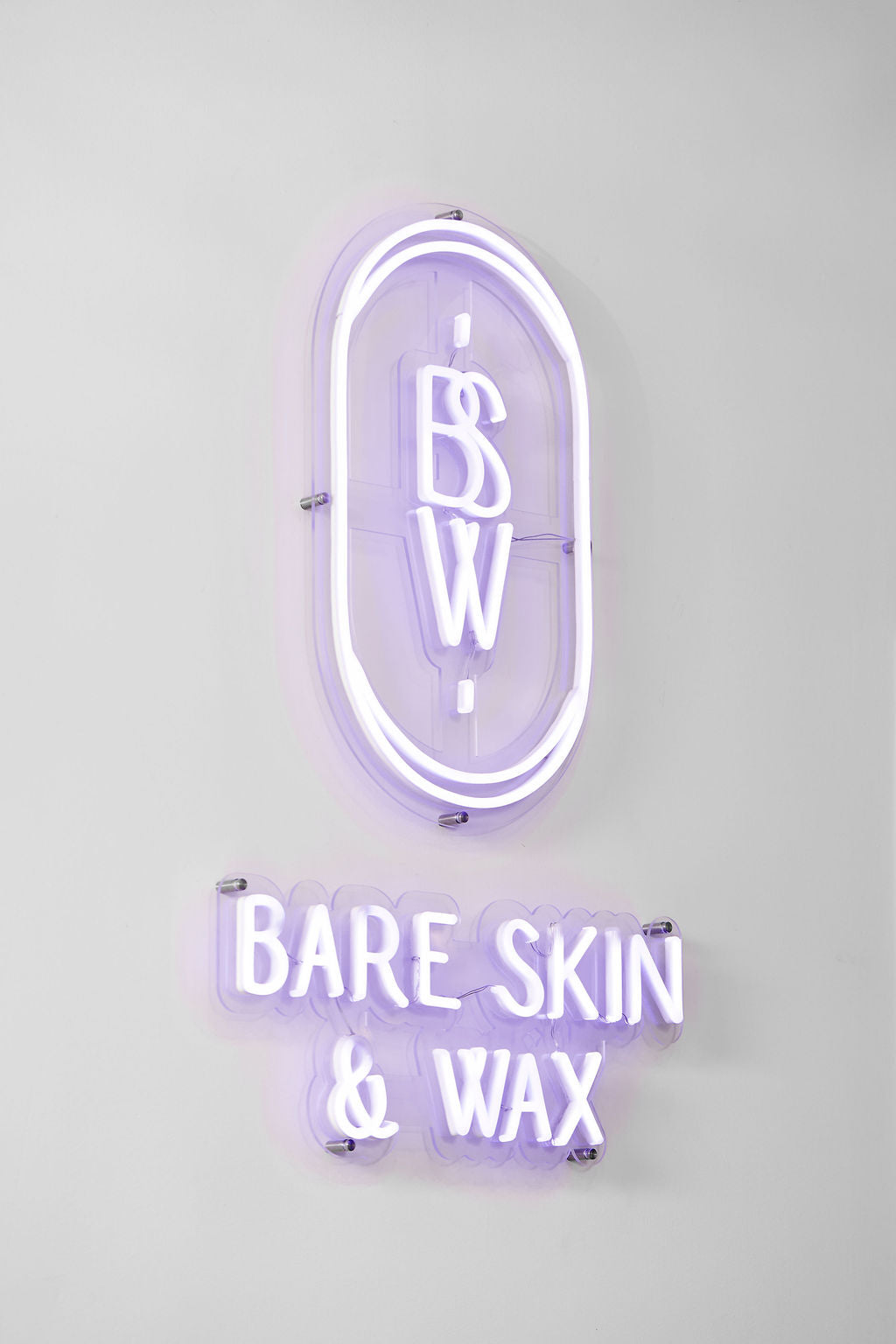 Neon sign with 'Bare Skin & Wax' on a white background