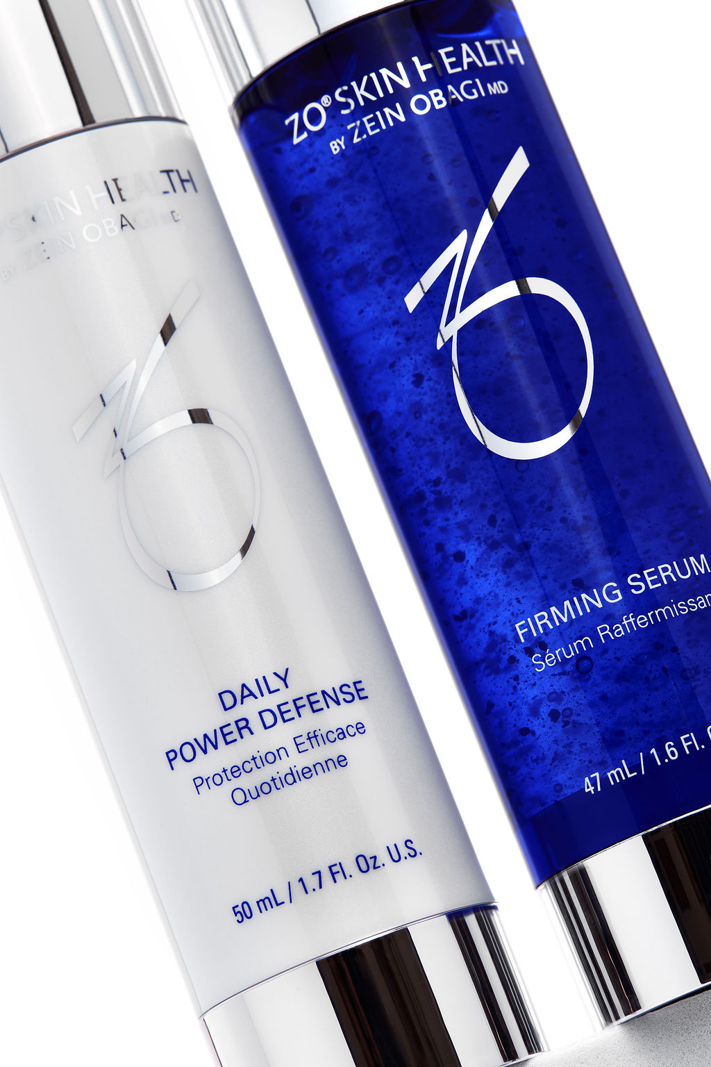 Two skincare bottles from ZO Skin Health, one white and one blue, on a light background.